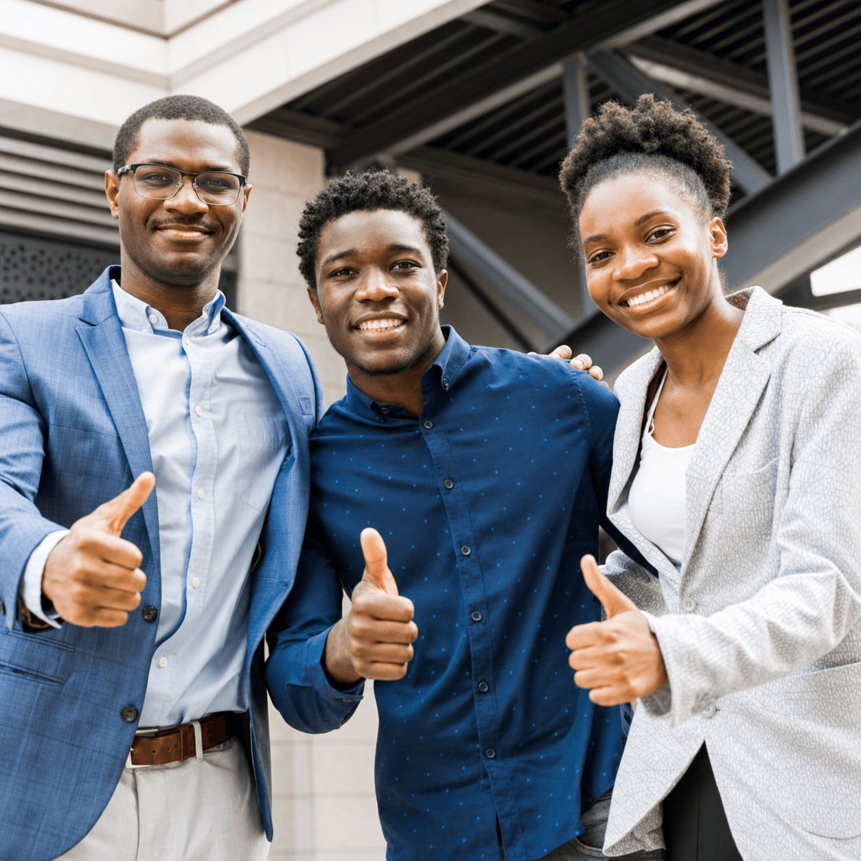 Three young professionals giving thumbs up